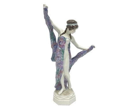 Goldscheider figure, female in multicoloured dress, holding up her skirts by the hem, on a heptagonal base, H41cm