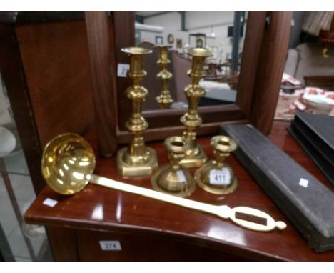A pair of Victorian brass candlesticks, a pair of squat brass candlesticks, a brass ladle and a carving set.
