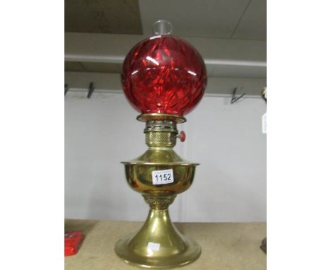 A brass oil lamp with ruby glass shade.
