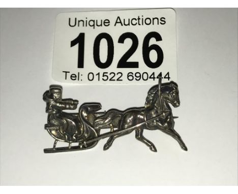 A white metal brooch being horse pulling sled (possibly Scandinavian).