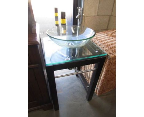 A modern glass wash basin on stand.,