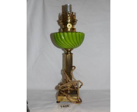 A French table lamp in the form of an oil lamp with green glass font and brass column,