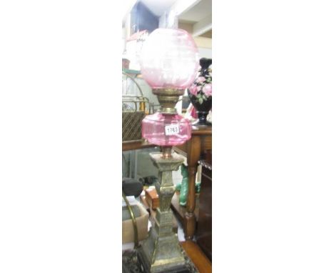An oriental style brass and cranberry glass oil lamp.