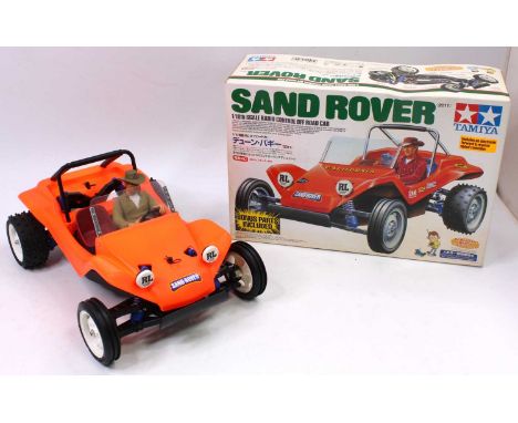 A Tamiya 1/10 scale radio controlled model of a Sand Rover off-road car, comprising fluorescent orange body with driver figur