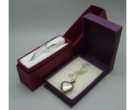 A silver bangle set with a diamond and a silver heart shaped pendant and chain
