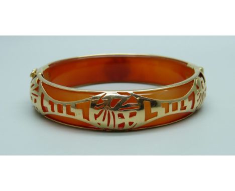 A yellow metal mounted jade bangle with oriental fretwork detail, stamped 14k