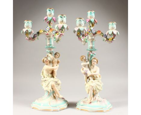 A PAIR OF CONTINENTAL PORCELAIN CANDELABRA, each with scrolling branches and figural base. 18ins high.