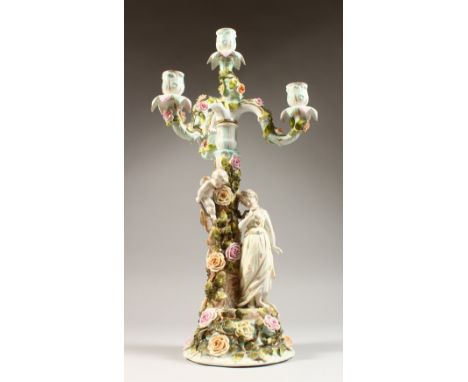 A SITZENDORF CANDELABRA, with three scrolling branches, the base with a young lady and cherub by a rose covered tree. 21ins h