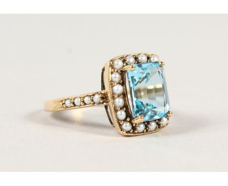 A 9CT GOLD EMERALD CUT BLUE TOPAZ AND SEED PEARL RING.