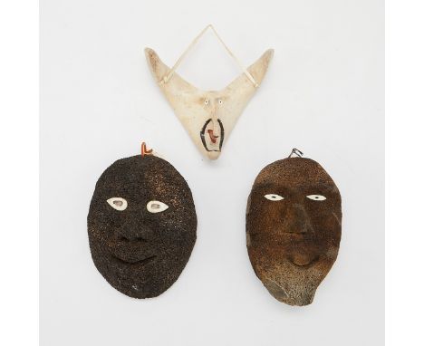 Group of three Native American Inuit carved bone masks. Two dark brown or black masks with white inlaid bone eyes.Height rang