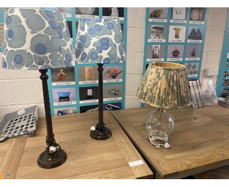 A pair of tall lamps with blue and white shades and a glass lamp with OKA pleated shade