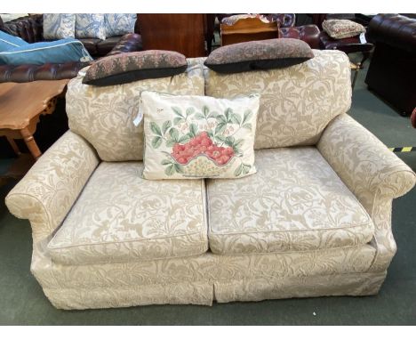 A two seater sofa, upholstered in a cream fabric with patterns of monkeys 