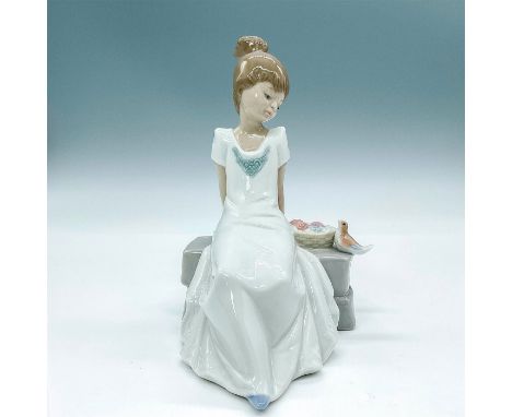 Glossy finish porcelain modeled as a young girl seated outside on a sunny day accompanied by a bird. Nao by Lladro backstamp.