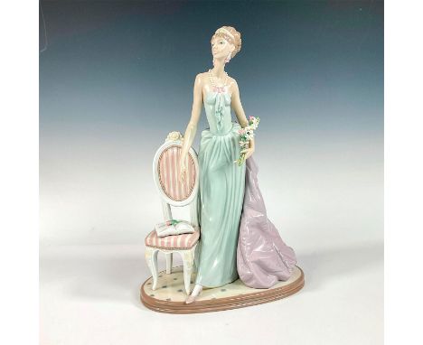 A stunning glazed figure of a woman in an elegant gown holding a bouquet of pink and white flowers. Lladro backstamp. This it