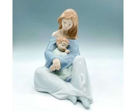 Glossy finish porcelain figure modeled as a mother caressing her young baby boy while he sleeps peacefully in her arms. Nao B