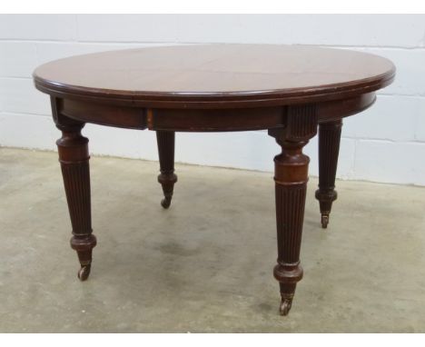 Late Victorian mahogany dining table with a moulded top and semi-circular ends on reeded turned tapering legs and brown ceram