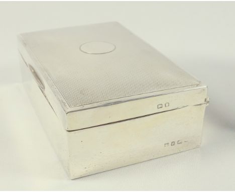 George V silver rectangular cigarette box with an engine turned cover with a vacant circular cartouche, by A &amp; J Zimmerma