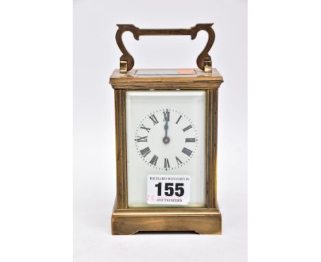 A BRASS FRAMED CARRIAGE CLOCK, four glass panels, white dial, roman numerals, approximate height 12cm, fitted with a scroll d