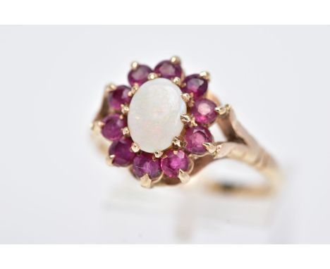 A 9CT GOLD OPAL AND RUBY CLUSTER RING, designed with a central oval cut opal, within a surround of circular cut rubies, bifur