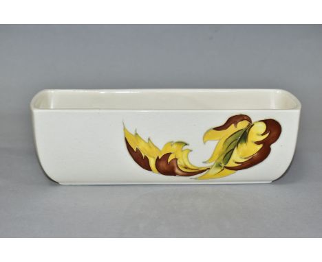 A MOORCROFT POTTERY RECTANGULAR FLOWER TROUGH, decorated with Leaves in the Wind pattern on a cream ground, bears blue paper 