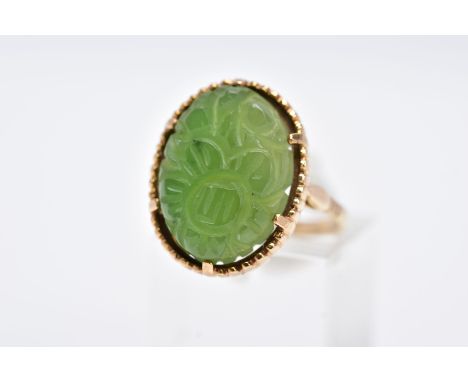 A 9CT GOLD, CARVED NEPHRITE CAMEO RING, of an oval form with a carved floral design, beaded surround, hallmarked 9ct gold Lon