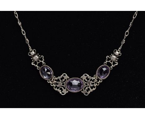 AN ARTS AND CRAFTS AMETHYST NECKLACE, designed with three collet set, oval mix cut amethysts, interspaced with openwork scrol