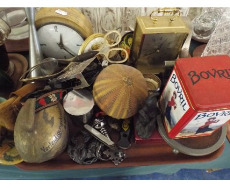 A Tray of Sundries to Include Mantle Clock, Cow Bell, Bovril Tin, Hole Puncher Etc. 