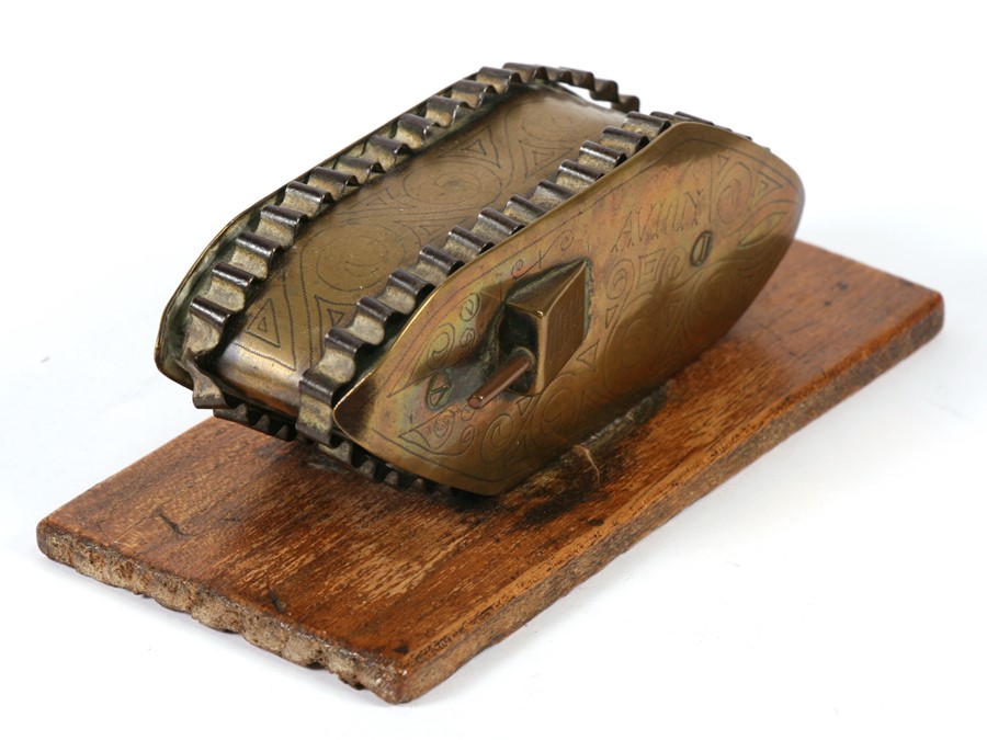 A WW1 brass trench art tank standing on a wooden base, with engraving ...