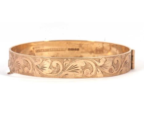 A 9ct bangle, with engraved decoration throughout, hinged with interlocking catch and safety chain, hallmarked Birmingham 198