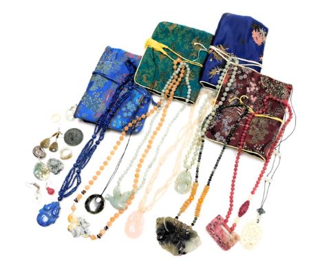 A group of Chinese jade and hardstone pendants, strings of beads, a ring, and jewellery pouches.
