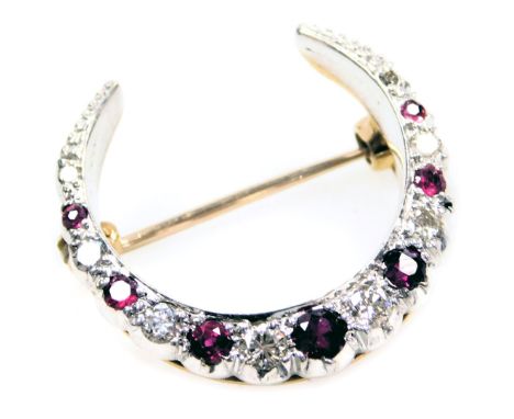 A ruby and diamond crescent moon shaped brooch, set with seven rubies, and eight diamonds at intervals, in white and yellow m