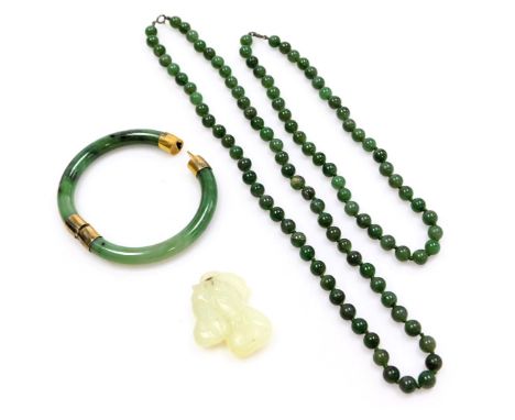 A jade bangle, with gilt metal snap clasp and mounts, stamped 925, two strings of jade beads, and a jade pendant formed as tw