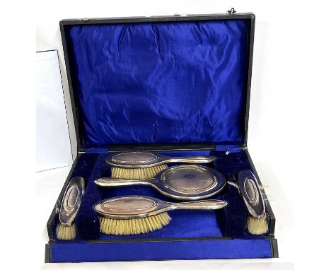 George V silver mounted cased dressing table set comprising a hand mirror, two hairbrushes and two clothes brushes, hallmarke