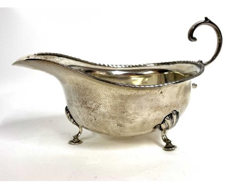 George V silver cream jug of typical form with a reeded detail border, flying cap leaf handle supported on three hoof feet, h