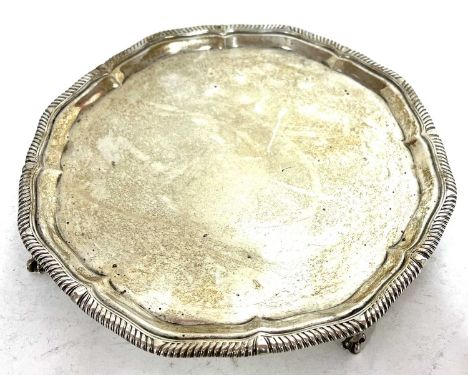 George V silver salver, the scalloped rim with gadrooned border supported on four claw and ball feet, 20cm in diameter, hallm