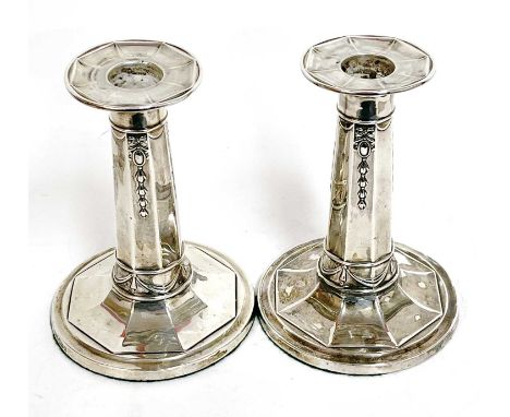 Pair of Edwardian small silver candlesticks of octagonal form, the columns decorated with ribbons to a spreading loaded base,