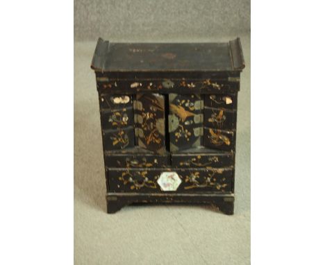 A Japanese Meiji period black lacquered tabletop cabinet, with a rising lid over two cupboard doors, above two short drawers,