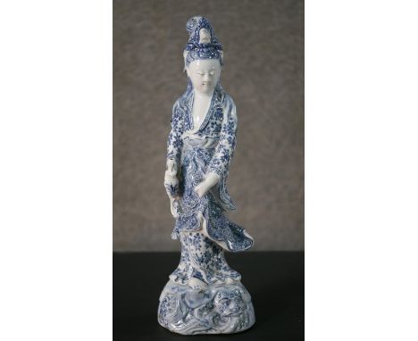 A Kangxi period Chinese hand painted blue and white porcelain figure of a female immortal. She is holding a vase and there is