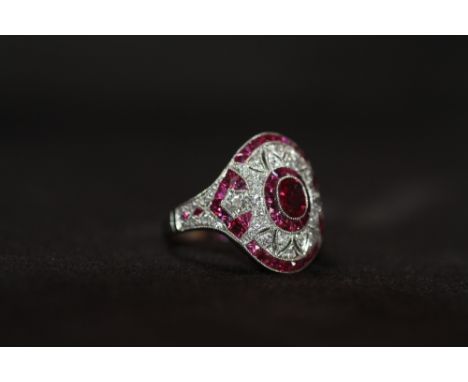 AN ORNATE PLATINUM RUBY AND DIAMOND DRESS RING, Set with an oval-cut ruby, calibre-cut rubies and RBC diamonds&nbsp;, Ring si