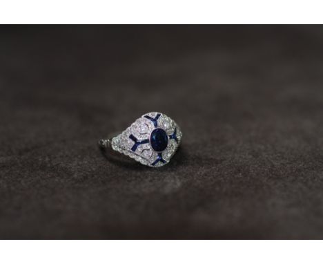 A VICTORIAN STYLE PLATINUM SAPPHIRE AND DIAMOND RING, set with a central oval-cut sapphire. The filigree mount is set with sa