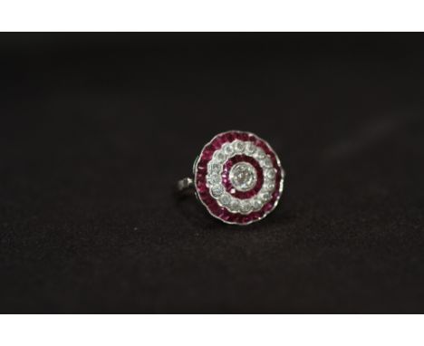 A PLATINUM RUBY AND DIAMOND RING, set with a central old-cut diamond, surrounded by a halo of calibre cut rubies, a halo of R