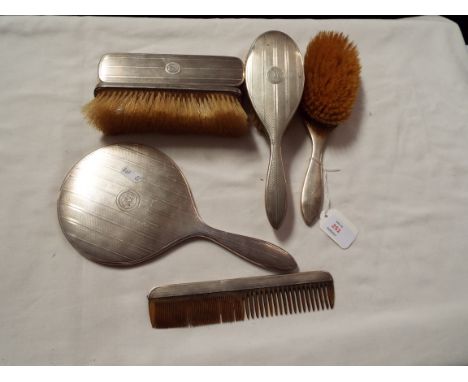A Birmingham 1914 silver backed grooming set with hand mirror by Mappin & Webb with engine turned decoration (five pieces in 