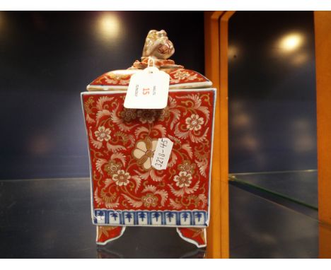 A Chinese Imari style caddy of square tapering form decorated with foliate panels the lid surmounted with a dog of fo and rai