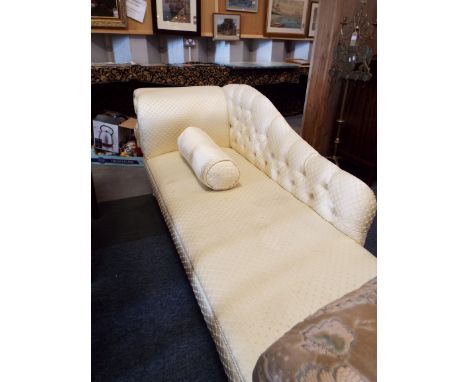 A cream upholstered scroll and button-back chaise lounge raised on cabriole shaped supports