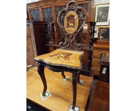 A circa 1890's carved Black Forest musical chair, the carved scrolled back having floral decoration and cartouche with inlaid