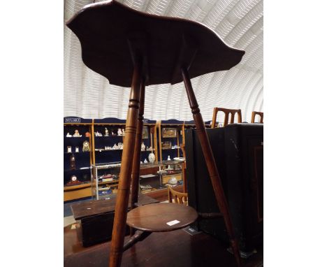 An early 20th C occasional table the shaped top over a circular under-tier and raised on three ring turned supports