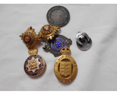 A gilt enamel Queens Royal Surrey Regiment badge, a silver Royal Army Reserve badge, a Mappin & Webb Ltd 1915 on war service 