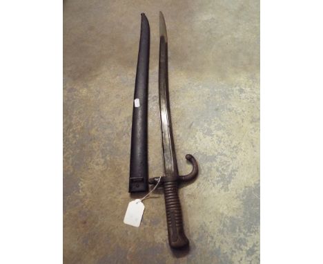 A French 1867 long bayonet having inscription to blade edge, brass grip and metal scabbard with number