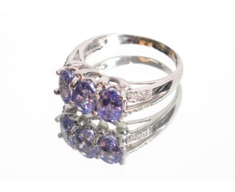 A 9ct white gold tanzanite three stone ring with chip diamond set shoulders, 4.5gms, ring size R