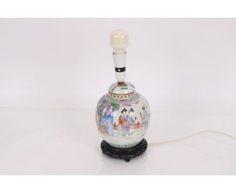 A Chinese ginger jar with figure decoration raised on carved hardwood stand, converted to a table lamp